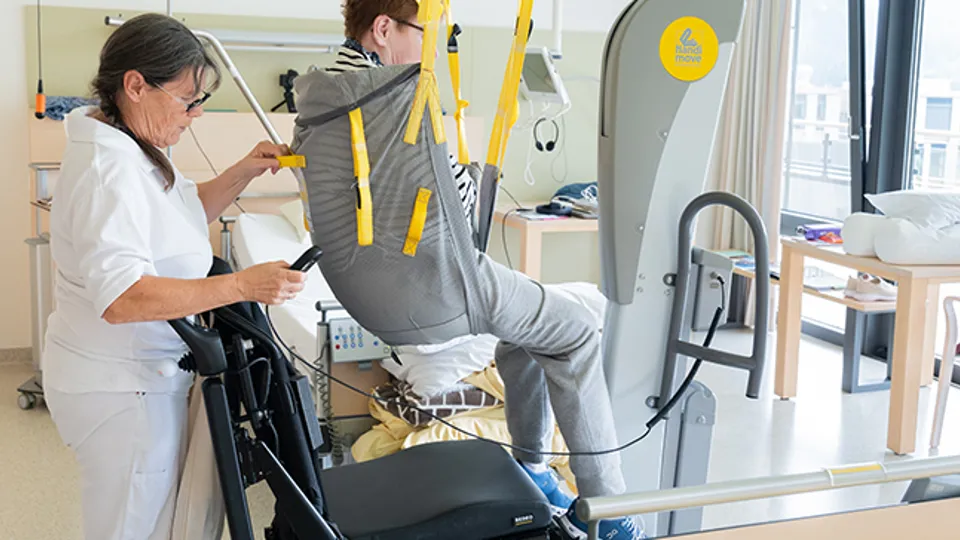 Verwendung des mobilen Lifters bei Patiententransfer in den Elektrorollstuhl durch Pflegeperson Verwendung des mobilen Lifters bei Patiententransfer in den Elektrorollstuhl durch Pflegeperson